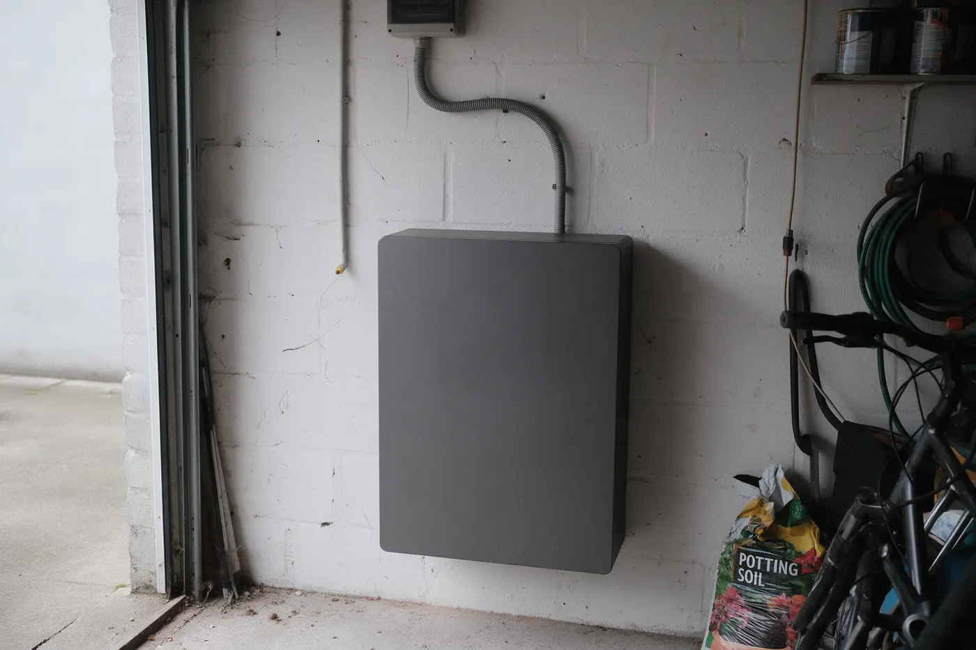 Thuisbatterij aan een garagewand, het toestel waar de jaarlijkse besparing vandaan komt