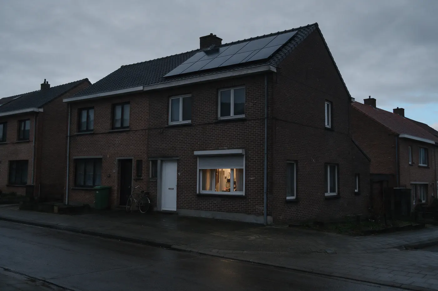 Misverstanden over de thuisbatterij: een Vlaamse rijwoning met zonnepanelen op het dak bij valavond