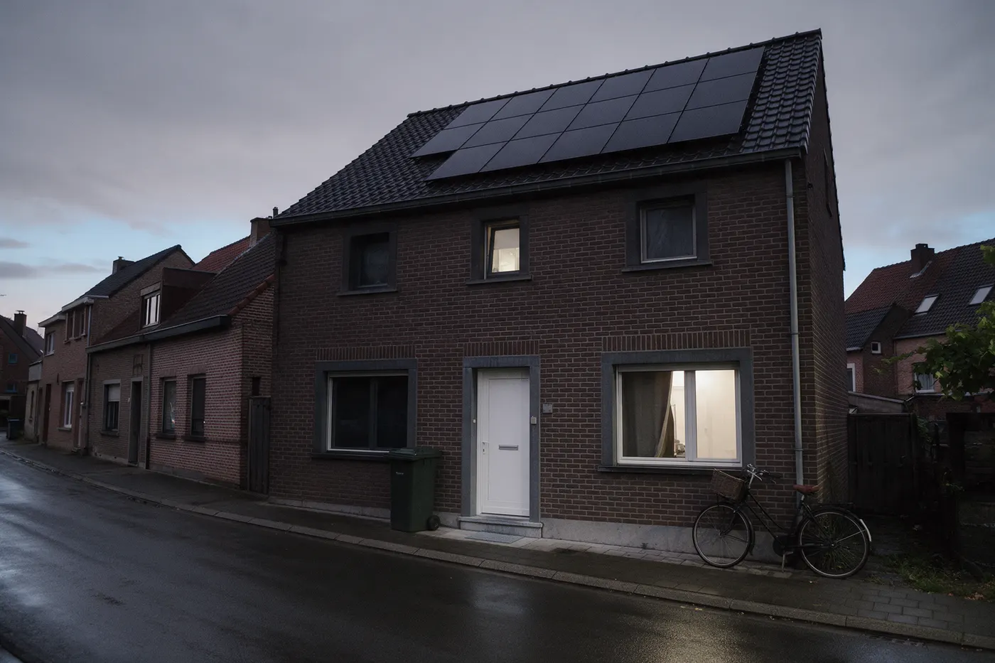 Vlaamse woonstraat bij valavond, waar gezinnen hun eigen verbruikscijfers opvragen voor onafhankelijk advies over een thuisbatterij