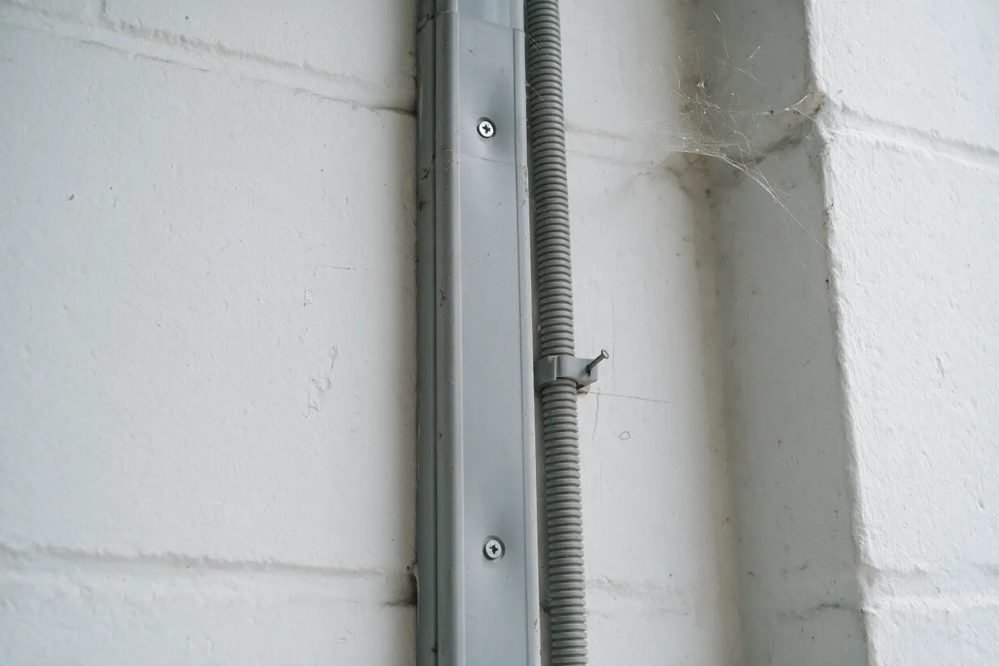Kabelgoot en wachtbuis langs een garagemuur bij een thuisbatterij