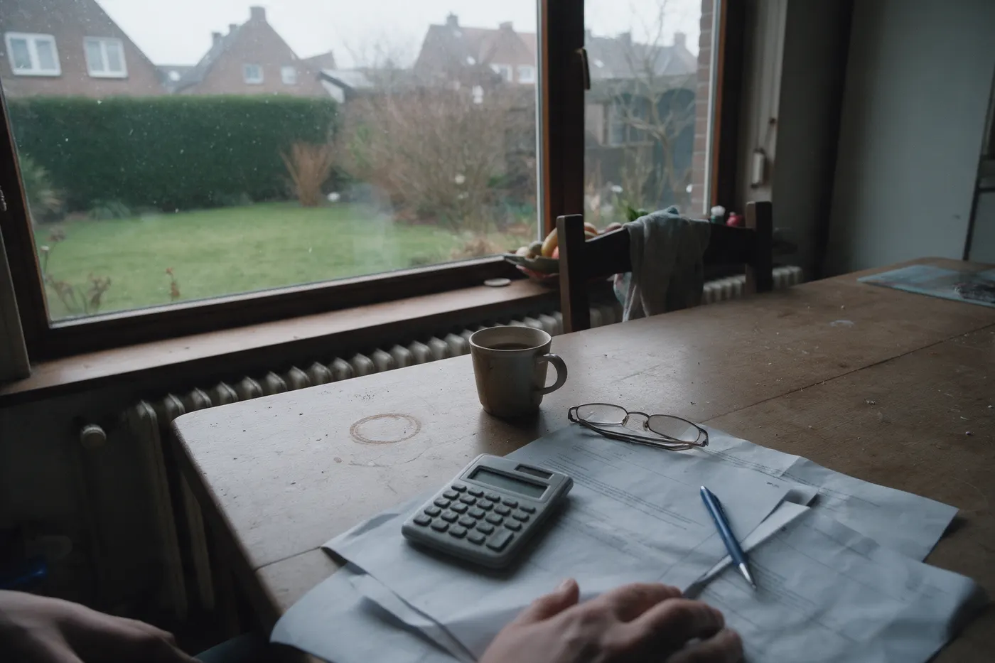 Keukentafel met papieren en een rekenmachine, waar iemand de rekening van een thuisbatterij richting 2030 maakt