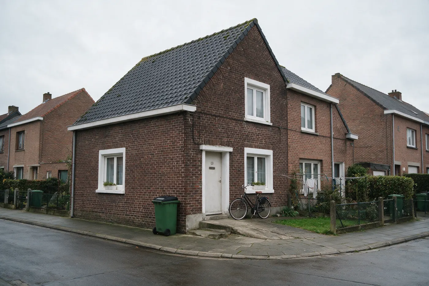 Oudere Vlaamse rijwoning van rode baksteen op een grijze dag