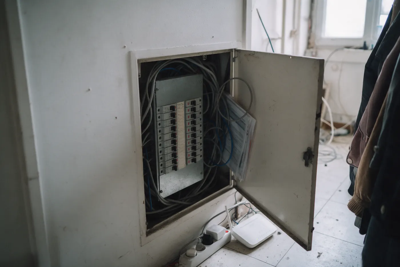 Open elektriciteitskast in een Vlaamse gang met stoffige bekabeling en een netwerkkabel, illustratie bij cyberveiligheid van een thuisbatterij