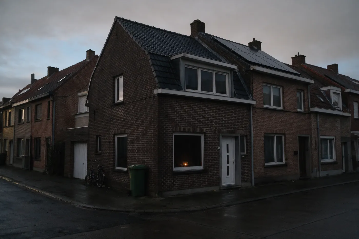 Noodstroom bij een thuisbatterij: Vlaamse rijwoning met zonnepanelen tijdens een stroomonderbreking, de hele straat donker bij valavond