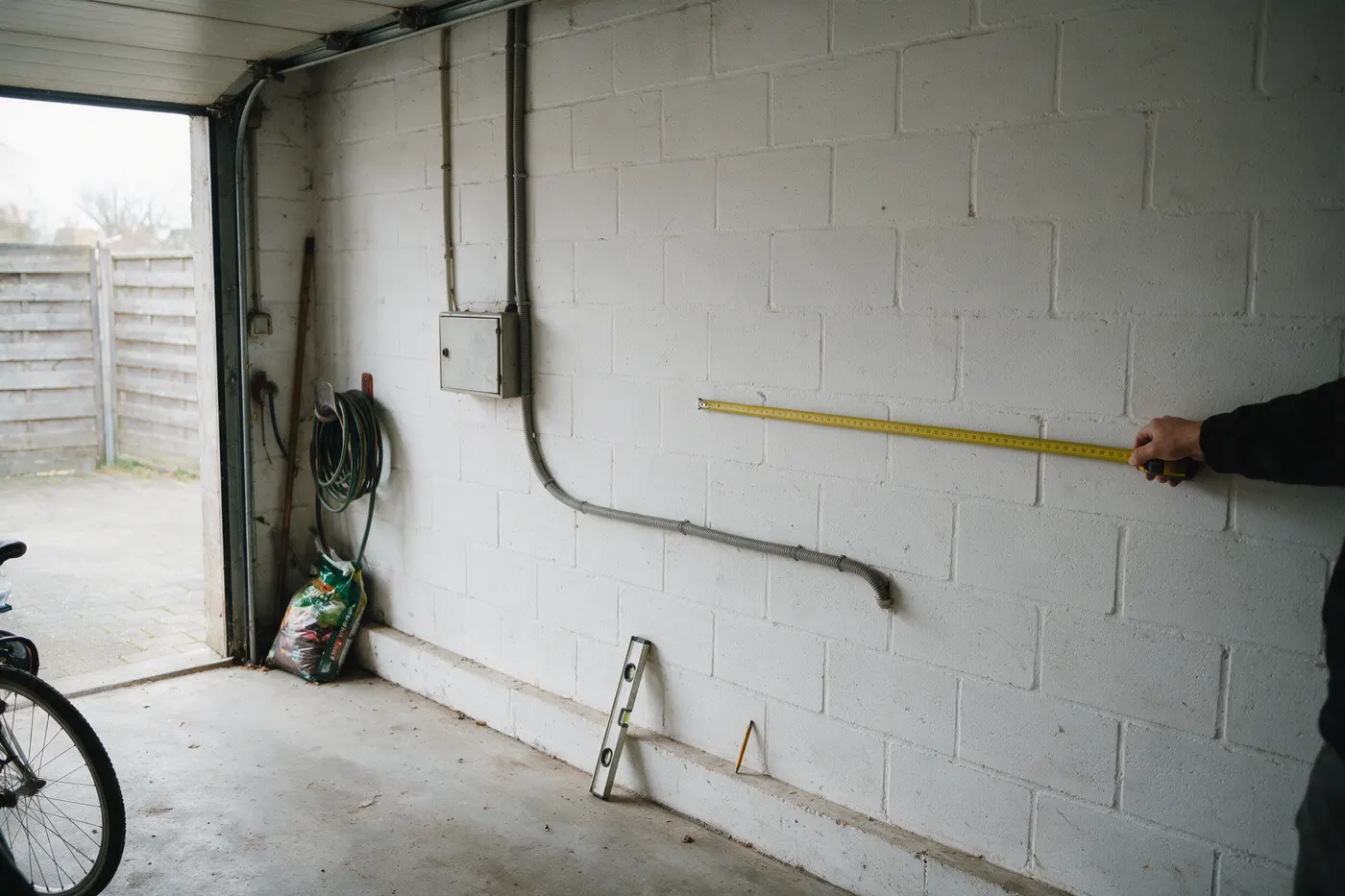 Muur in een garage wordt opgemeten voor de plaatsing van een thuisbatterij