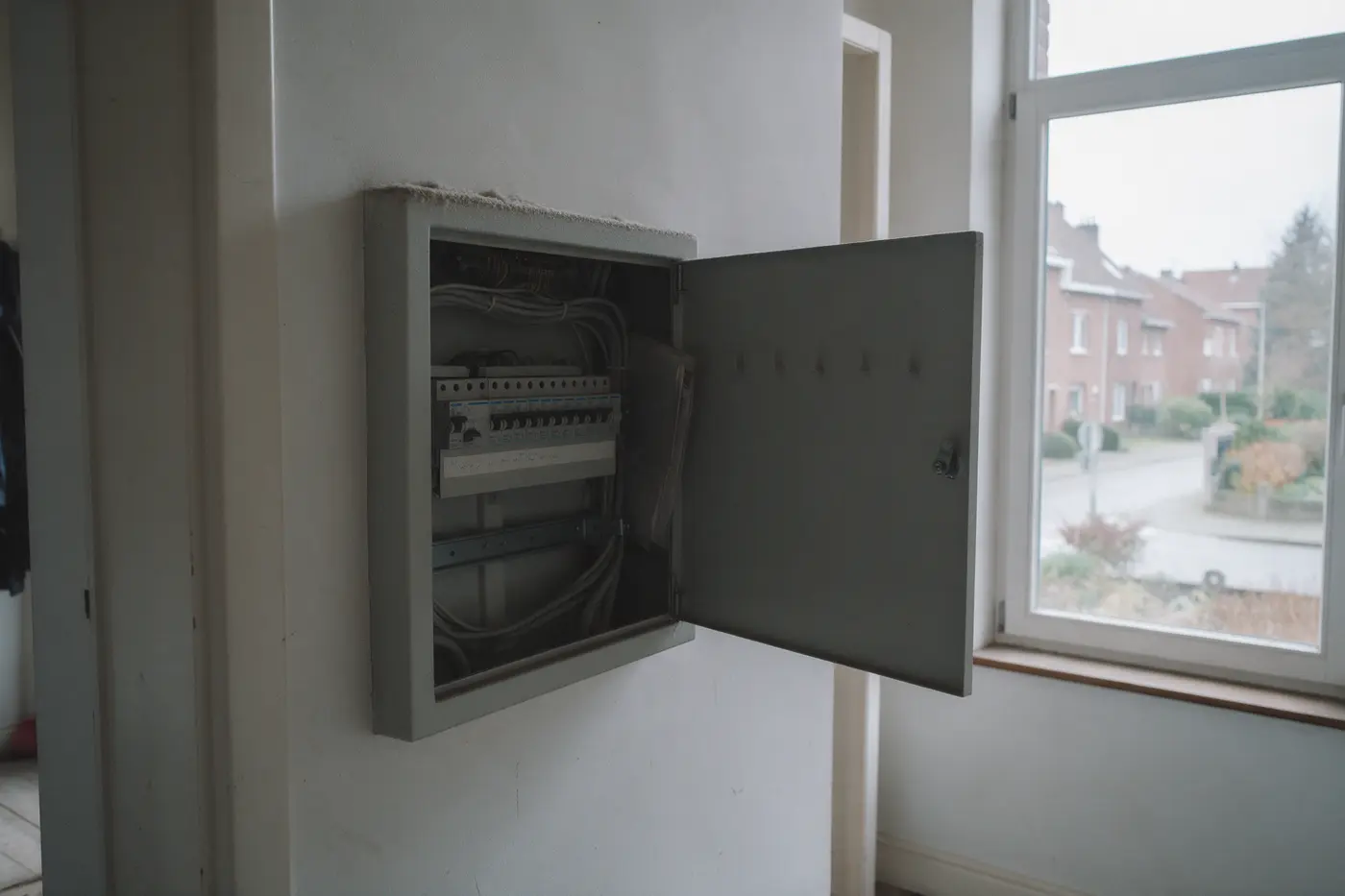 Open meterkast in een gang van een Vlaamse woning met een rij zekeringen en kabels, illustratie bij de eigen cijfers achter een thuisbatterij-onderzoek