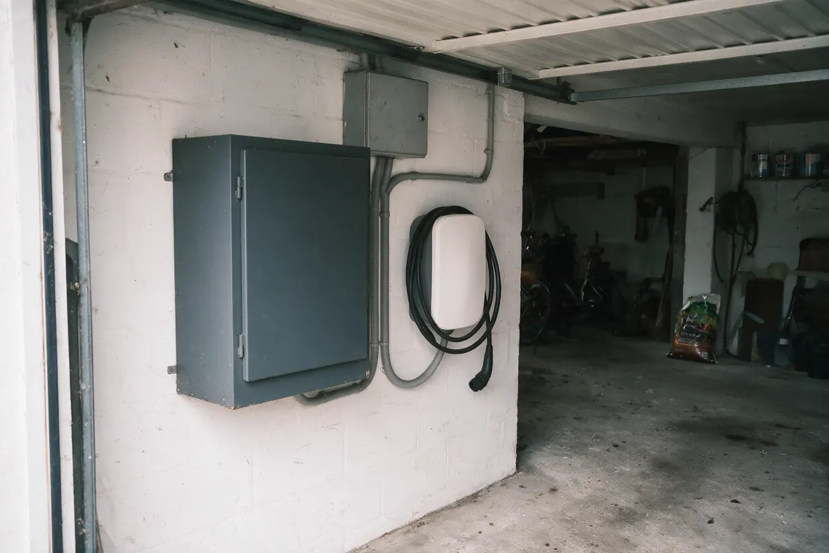 Thuisbatterij en laadpaal naast elkaar aan de wand in een Vlaamse garage